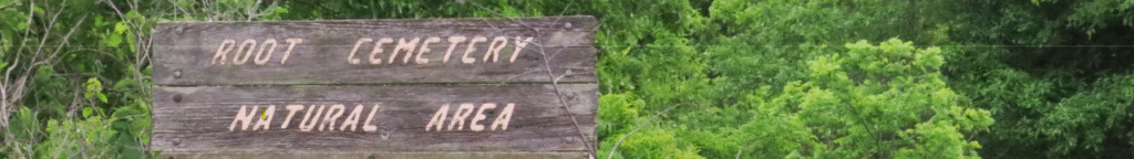 Weathered sign saying "Root Cemetery Natural Area," with trees in the background.